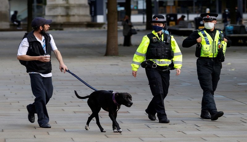 Polisi memakai masker sambil membawa anjing, ditengah wabah penyakit virus corona. FOTO: Phil Noble/Reuters/Antara Polisi memakai masker sambil membawa anjing, ditengah wabah penyakit virus corona. FOTO: Phil Noble/Reuters/Antara