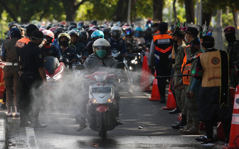 Petugas menyemprotkan larutan disinfektan ke kendaraan bermotor yang memasuki Surabaya di pintu keluar Jembatan Suramadu, Surabaya, Jawa Timur, Senin (20/4/2020). -Foto: Antara/Didik Suhartono Petugas menyemprotkan larutan disinfektan ke kendaraan bermotor yang memasuki Surabaya di pintu keluar Jembatan Suramadu, Surabaya, Jawa Timur, Senin (20/4/2020). -Foto: Antara/Didik Suhartono