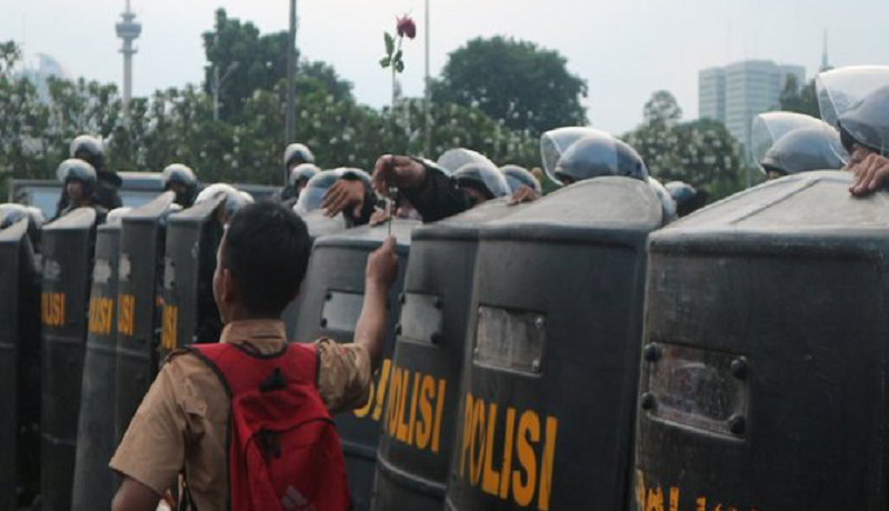Seorang pelajar memberikan setangkai bunga kepada polisi saat demo di depan gedung DPR Jakarta. Foto: Antara Seorang pelajar memberikan setangkai bunga kepada polisi saat demo di depan gedung DPR Jakarta. Foto: Antara