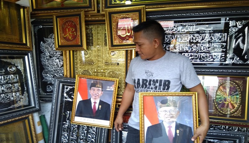 Pedagang bingkai memperlihatkan bingkai foto presiden Jokowi-Ma'ruf yang dijualnya. Foto: Antara Pedagang bingkai memperlihatkan bingkai foto presiden Jokowi-Ma'ruf yang dijualnya. Foto: Antara