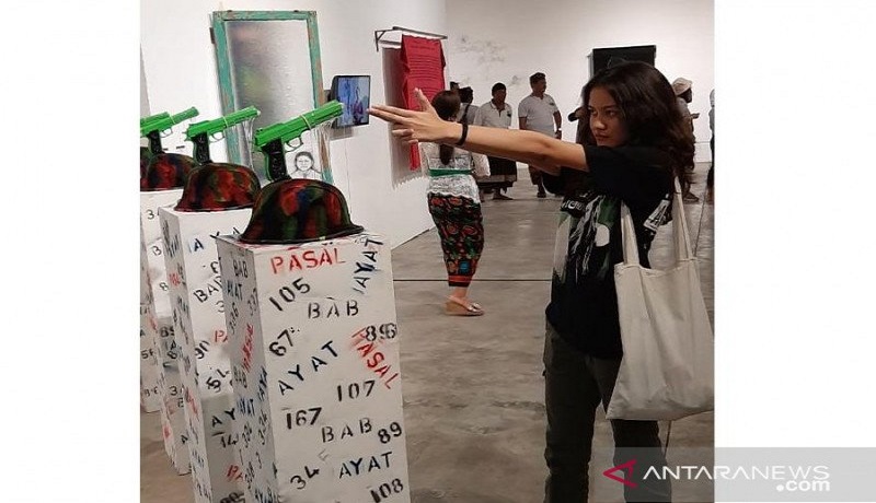 Pengunjung pameran yang tengah asyik melihat sambil memperagakan aksi memegang pistol di depan seni instalasi karya Ketut Putrayasa. Foto: Antara Pengunjung pameran yang tengah asyik melihat sambil memperagakan aksi memegang pistol di depan seni instalasi karya Ketut Putrayasa. Foto: Antara