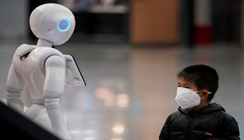 Seorang anak lelaki memperhatikan robot sambil memakai masker di Bandara Internasional Pudong di Shanghai, China. Foto: Antara Seorang anak lelaki memperhatikan robot sambil memakai masker di Bandara Internasional Pudong di Shanghai, China. Foto: Antara