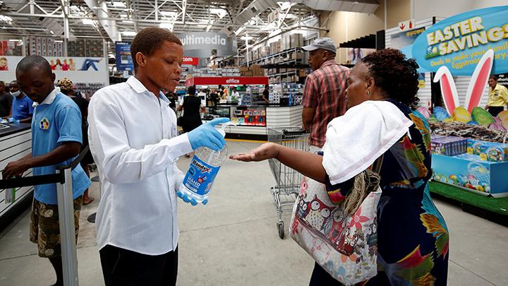 Petugas memberikan cairan hand sanitizer pada warga yang mengantre untuk membeli bahan makanan di supermarket, menjelang diberlakukannya lockdown selama 21 hari, sebagai upaya mencegah penyebaran Virus Corona di Johannesburg, Afrika Selatan, 24 Maret 2020 Petugas memberikan cairan hand sanitizer pada warga yang mengantre untuk membeli bahan makanan di supermarket, menjelang diberlakukannya lockdown selama 21 hari, sebagai upaya mencegah penyebaran Virus Corona di Johannesburg, Afrika Selatan, 24 Maret 2020