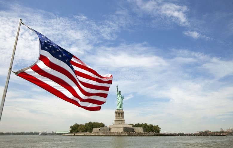 Bendera AS dengan latar belakang Patung Liberty di New York. Foto: Reuters. Bendera AS dengan latar belakang Patung Liberty di New York. Foto: Reuters.