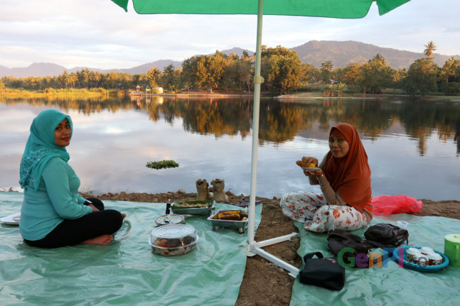 Dua orang wisatawan sedang menikmati kuliner di tepi Danau Perintis, Bone Bolango. Dua orang wisatawan sedang menikmati kuliner di tepi Danau Perintis, Bone Bolango.